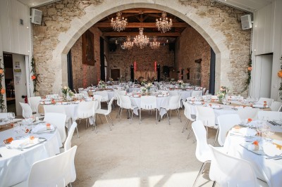 Ancien moulin en pierre avec une grande roue à aubes, bordé par un cours d'eau et entouré de végétation.