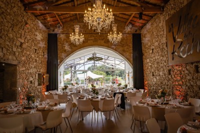 Ancien moulin en pierre avec une grande roue à aubes, bordé par un cours d'eau et entouré de végétation.