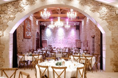 Ancien moulin en pierre avec une grande roue à aubes, bordé par un cours d'eau et entouré de végétation.