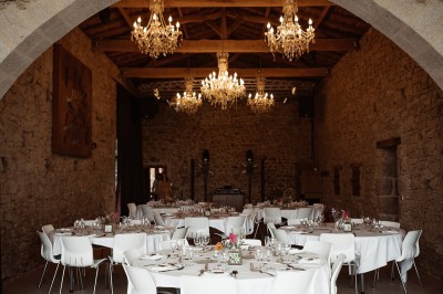 Ancien moulin en pierre avec une grande roue à aubes, bordé par un cours d'eau et entouré de végétation.