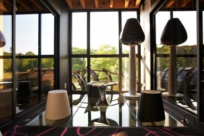 Salle de réception éclairée en rose avec un buffet dressé et des tables hautes décorées de petites lampes.