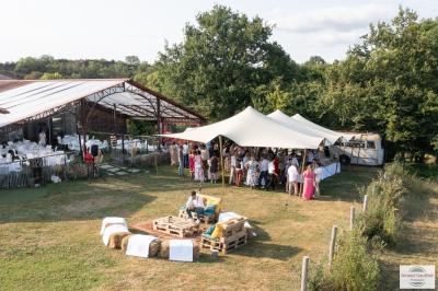 Salle de réception éclairée en rose avec un buffet dressé et des tables hautes décorées de petites lampes.
