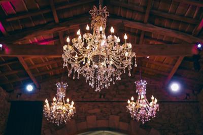 Salle de réception éclairée en rose avec un buffet dressé et des tables hautes décorées de petites lampes.