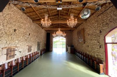 Salle de réception éclairée en rose avec un buffet dressé et des tables hautes décorées de petites lampes.