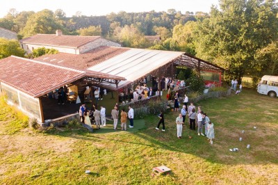 Bâtiment en pierre au bord d'une rivière entourée de végétation, avec un pont en arrière-plan sous un ciel dégagé.