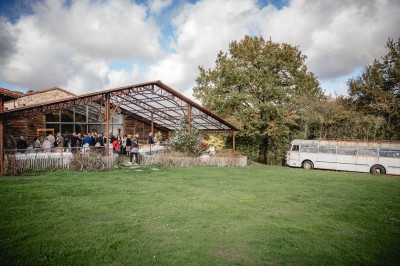 Bâtiment en pierre au bord d'une rivière entourée de végétation, avec un pont en arrière-plan sous un ciel dégagé.