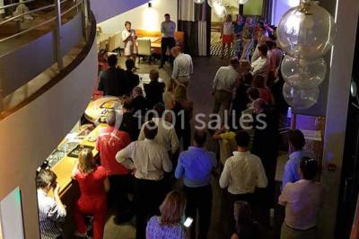 Des personnes se servent à un buffet varié disposé sur des tables rondes dans une salle lumineuse.