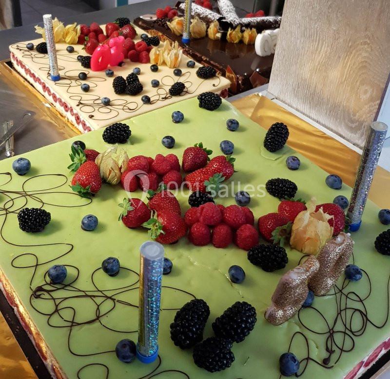 Gâteaux décorés de fruits rouges, noirs et jaunes sur des glaçages colorés, avec des éléments décoratifs festifs.