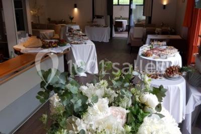 Des personnes se servent à un buffet varié disposé sur des tables rondes dans une salle lumineuse.