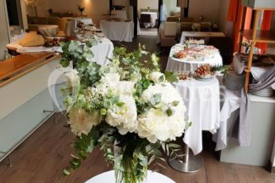 Buffet avec des plats variés, dont des salades, du saumon fumé et des fruits, décoré d'un bouquet de fleurs violettes et…