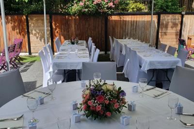 Buffet avec des plats variés, dont des salades, du saumon fumé et des fruits, décoré d'un bouquet de fleurs violettes et…