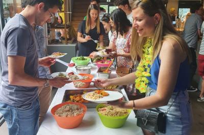 Buffet avec des plats variés, dont des salades, du saumon fumé et des fruits, décoré d'un bouquet de fleurs violettes et…