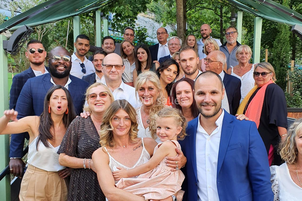 Groupe de personnes posant ensemble en extérieur sous une arche, entourées de verdure.