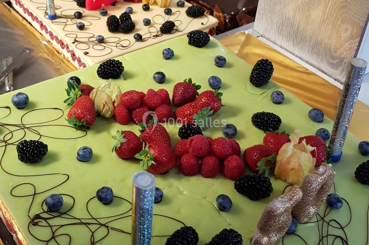 Gâteaux décorés de fruits rouges, myrtilles, physalis et mûres, avec des ornements en chocolat et bougies scintillantes.
