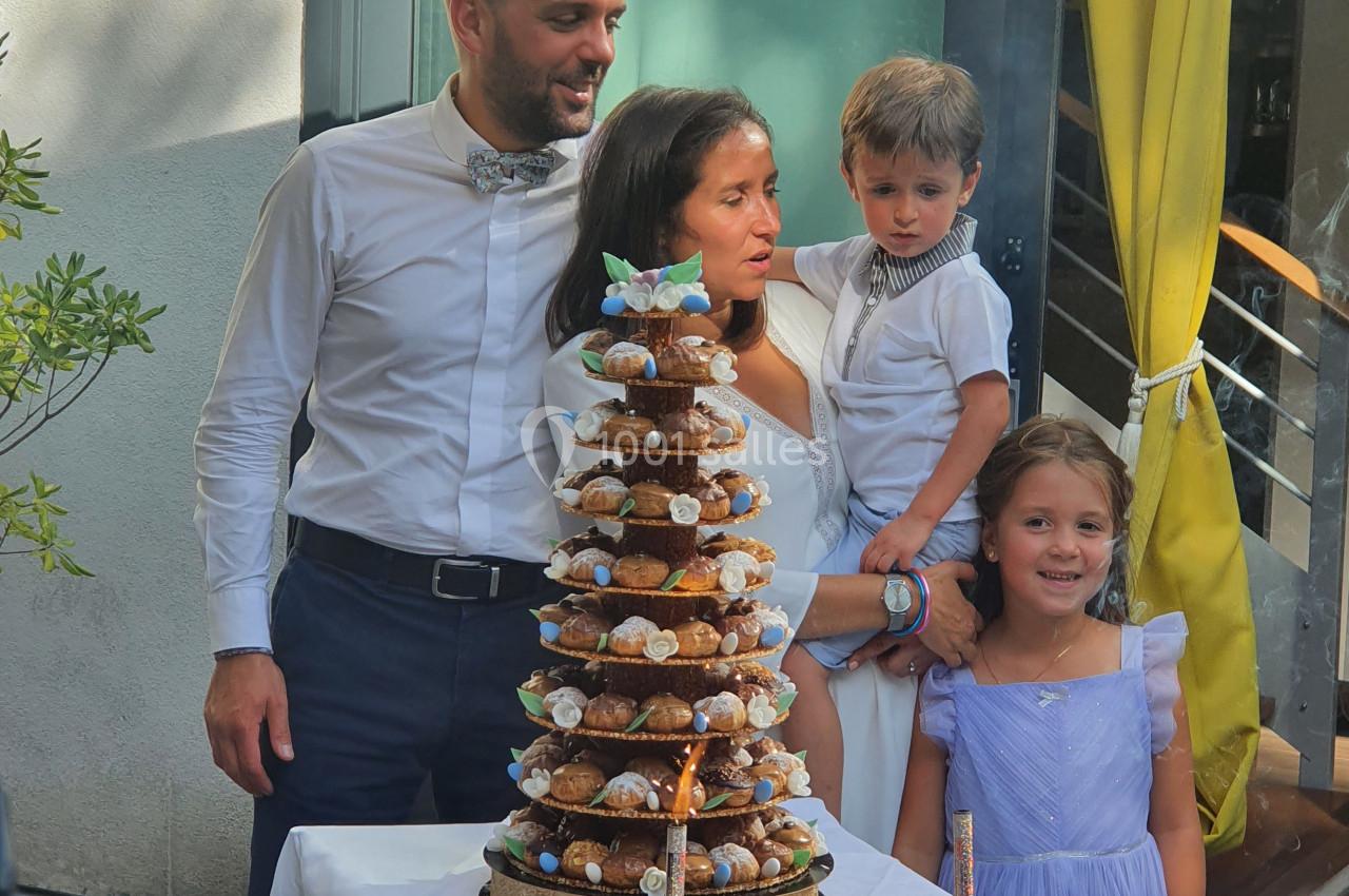 Une famille réunie autour d'une pièce montée et de gâteaux lors d'une célébration en extérieur.