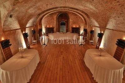 Vue nocturne d'une réception dans une tente éclairée, installée devant un bâtiment de style château.