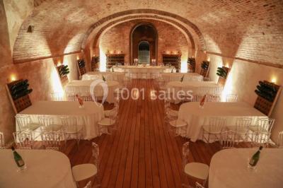 Vue nocturne d'une réception dans une tente éclairée, installée devant un bâtiment de style château.