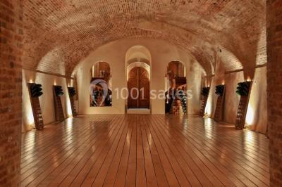 Vue nocturne d'une réception dans une tente éclairée, installée devant un bâtiment de style château.