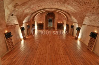 Vue nocturne d'une réception dans une tente éclairée, installée devant un bâtiment de style château.