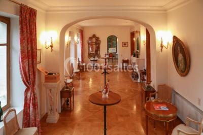 Vue nocturne d'une réception dans une tente éclairée, installée devant un bâtiment de style château.