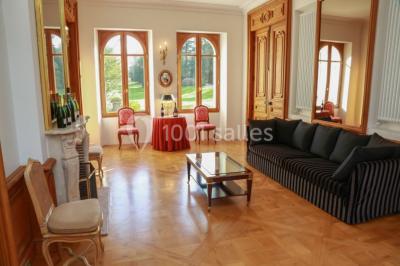 Vue nocturne d'une réception dans une tente éclairée, installée devant un bâtiment de style château.