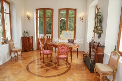 Vue nocturne d'une réception dans une tente éclairée, installée devant un bâtiment de style château.