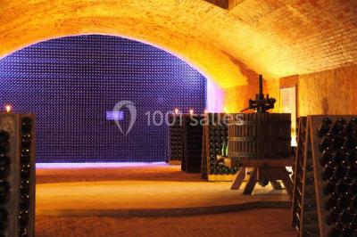 Vue nocturne d'une réception dans une tente éclairée, installée devant un bâtiment de style château.