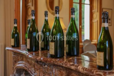 Vue nocturne d'une réception dans une tente éclairée, installée devant un bâtiment de style château.