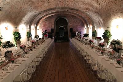 Vue nocturne d'une réception dans une tente éclairée, installée devant un bâtiment de style château.
