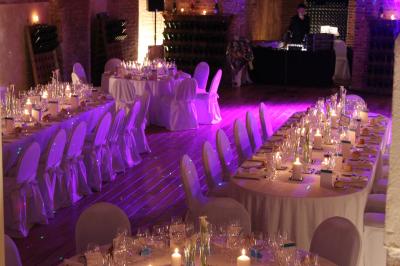 Vue nocturne d'une réception dans une tente éclairée, installée devant un bâtiment de style château.