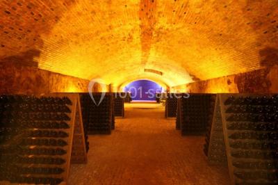 Des bouteilles de vin blanc dans une caisse en bois, avec un bar en bois et des tabourets en arrière-plan.