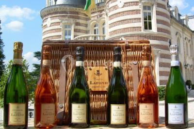 Des bouteilles de vin blanc dans une caisse en bois, avec un bar en bois et des tabourets en arrière-plan.