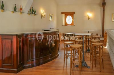 Des bouteilles de vin blanc dans une caisse en bois, avec un bar en bois et des tabourets en arrière-plan.