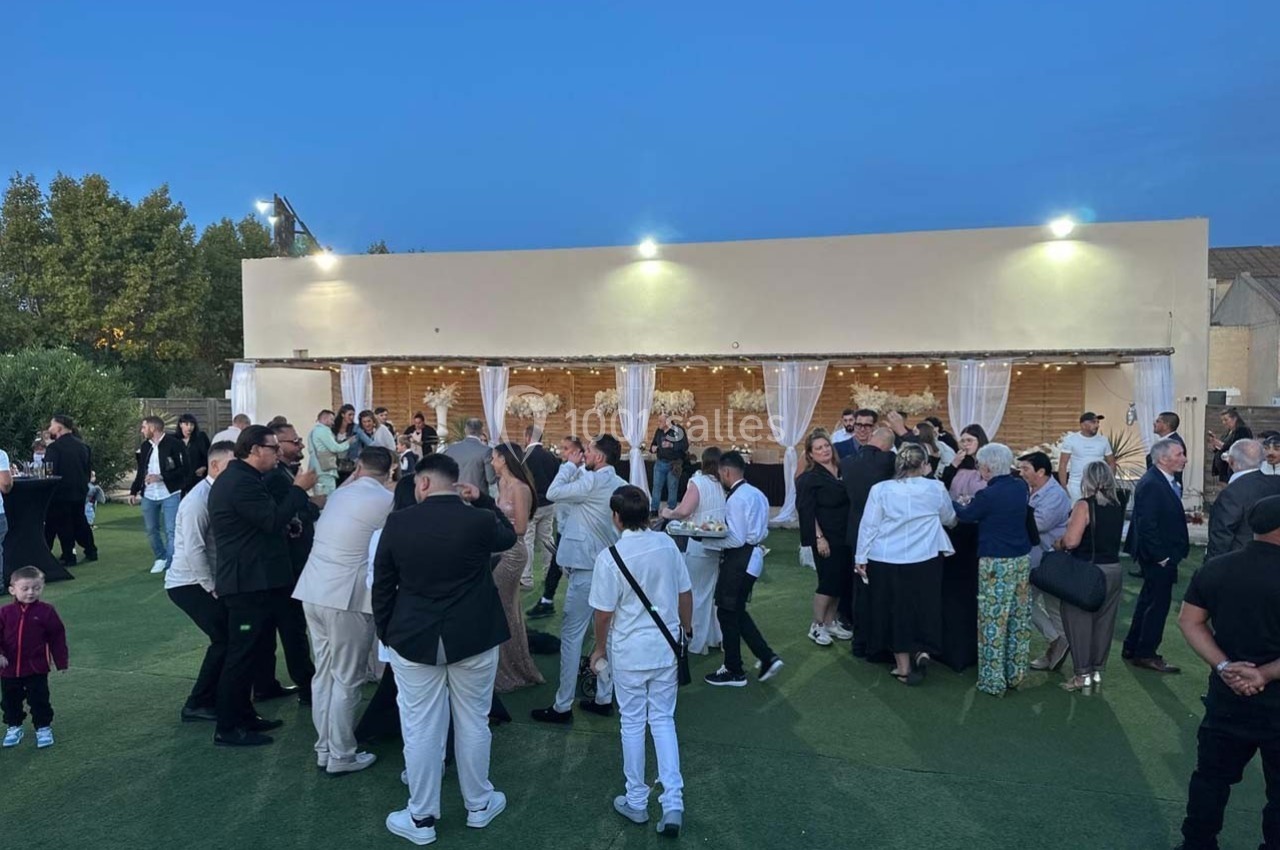 Groupe de personnes rassemblées en extérieur devant un bâtiment éclairé, lors d'un événement en soirée.