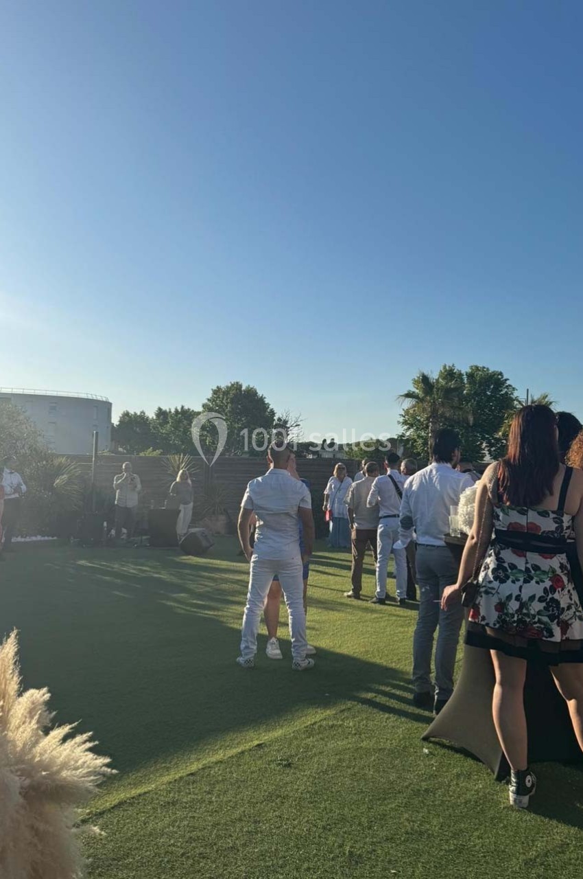 Des personnes discutent en extérieur sur une pelouse par une journée ensoleillée, avec des arbres en arrière-plan.