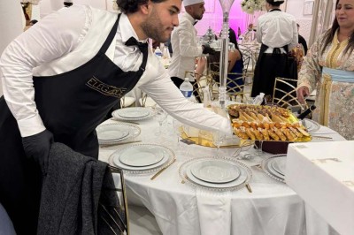 Assiette avec un jarret d'agneau en sauce et un millefeuille de légumes, servie sur une table dressée.