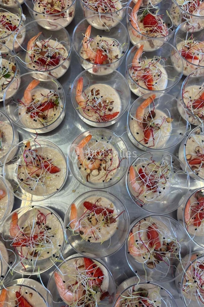 Verrines garnies de crevettes, fraises, pousses germées et éclats de noix, disposées sur un plateau argenté.