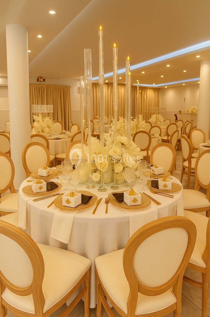 Salle de réception élégante avec table ronde décorée de fleurs blanches, bougies et chaises en bois clair.