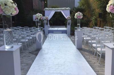 Salon avec canapé beige, table basse ronde, commode en bois sculpté et sol en carreaux décoratifs.