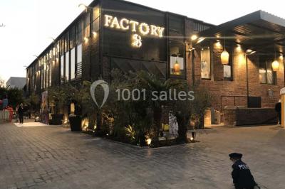 Salon avec canapé beige, table basse ronde, commode en bois sculpté et sol en carreaux décoratifs.