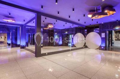 Salon avec canapé beige, table basse ronde, commode en bois sculpté et sol en carreaux décoratifs.