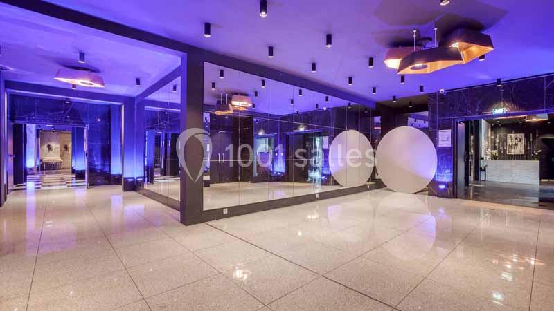 Salle moderne avec sol en marbre, éclairage tamisé, murs vitrés et décorations lumineuses circulaires.