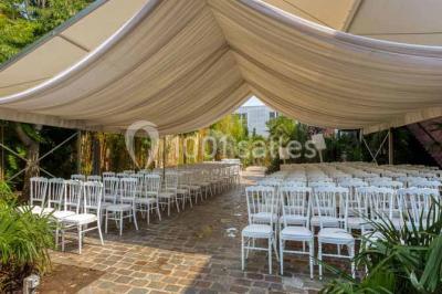 Salon avec canapé beige, table basse ronde, commode en bois sculpté et sol en carreaux décoratifs.