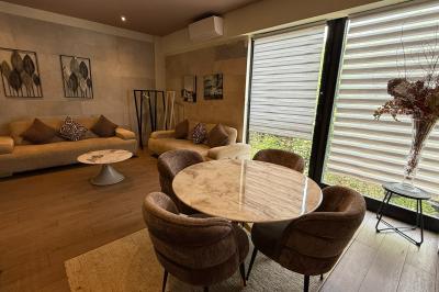 Salon avec canapé beige, table basse ronde, commode en bois sculpté et sol en carreaux décoratifs.