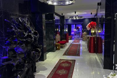 Salon avec canapé beige, table basse ronde, commode en bois sculpté et sol en carreaux décoratifs.