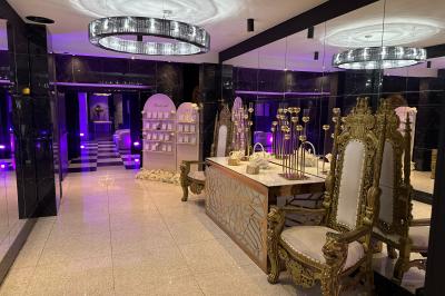 Salon avec canapé beige, table basse ronde, commode en bois sculpté et sol en carreaux décoratifs.