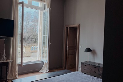 Miniature Chambre 2 Vue sur une piscine extérieure entourée de pelouse, avec un lac et des arbres en arrière-plan sous un ciel dégagé.