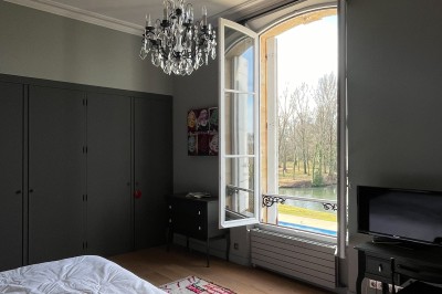 Miniature Chambre 6 Vue sur une piscine extérieure entourée de pelouse, avec un lac et des arbres en arrière-plan sous un ciel dégagé.