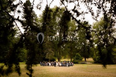 Table de réception élégamment dressée avec nappes blanches, verres, couverts, fleurs et bouteilles disposés harmonieusement.