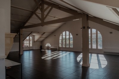 Table de réception élégamment dressée avec nappes blanches, verres, couverts, fleurs et bouteilles disposés harmonieusement.